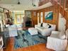 Living area featuring wood finished floors, wooden walls, a wall mounted air conditioner, a fireplace, and a high ceiling