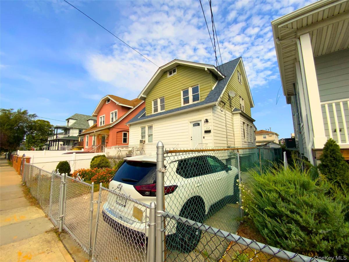 View of property exterior featuring a shingled roof and a gate