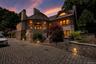 Stone and stucco exterior featuring multiple chimneys and a distinctive rounded facade