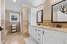 Bathroom with double vanity, wainscoting, tile walls, light tile patterned floors, and crown molding