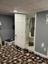 Recessed ceiling lighting, white paneled door, three-piece bathroom with glass-enclosed shower, tiled flooring in bathroom, light gray wall paint