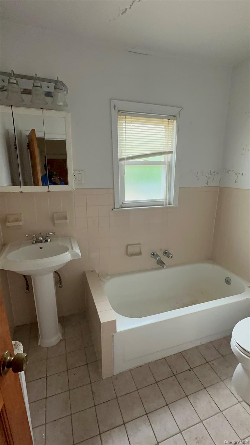 Full bathroom featuring a garden tub and tile patterned flooring