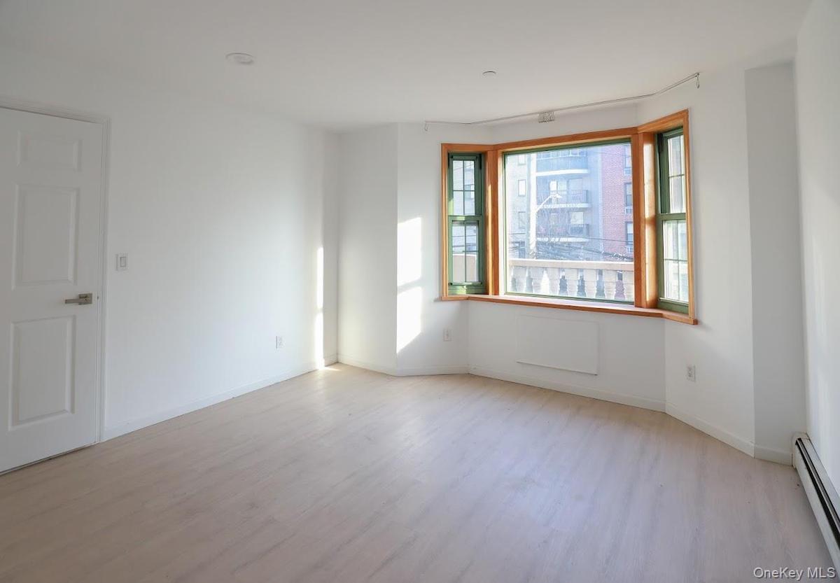 Spare room with a baseboard radiator and light wood-type flooring