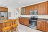 Kitchen featuring stainless steel appliances, wood cabinetry, granite-style countertops, and tile flooring
