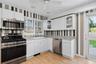 Kitchen featuring wood-finish flooring, white cabinetry, and access to the rear dining pavilion