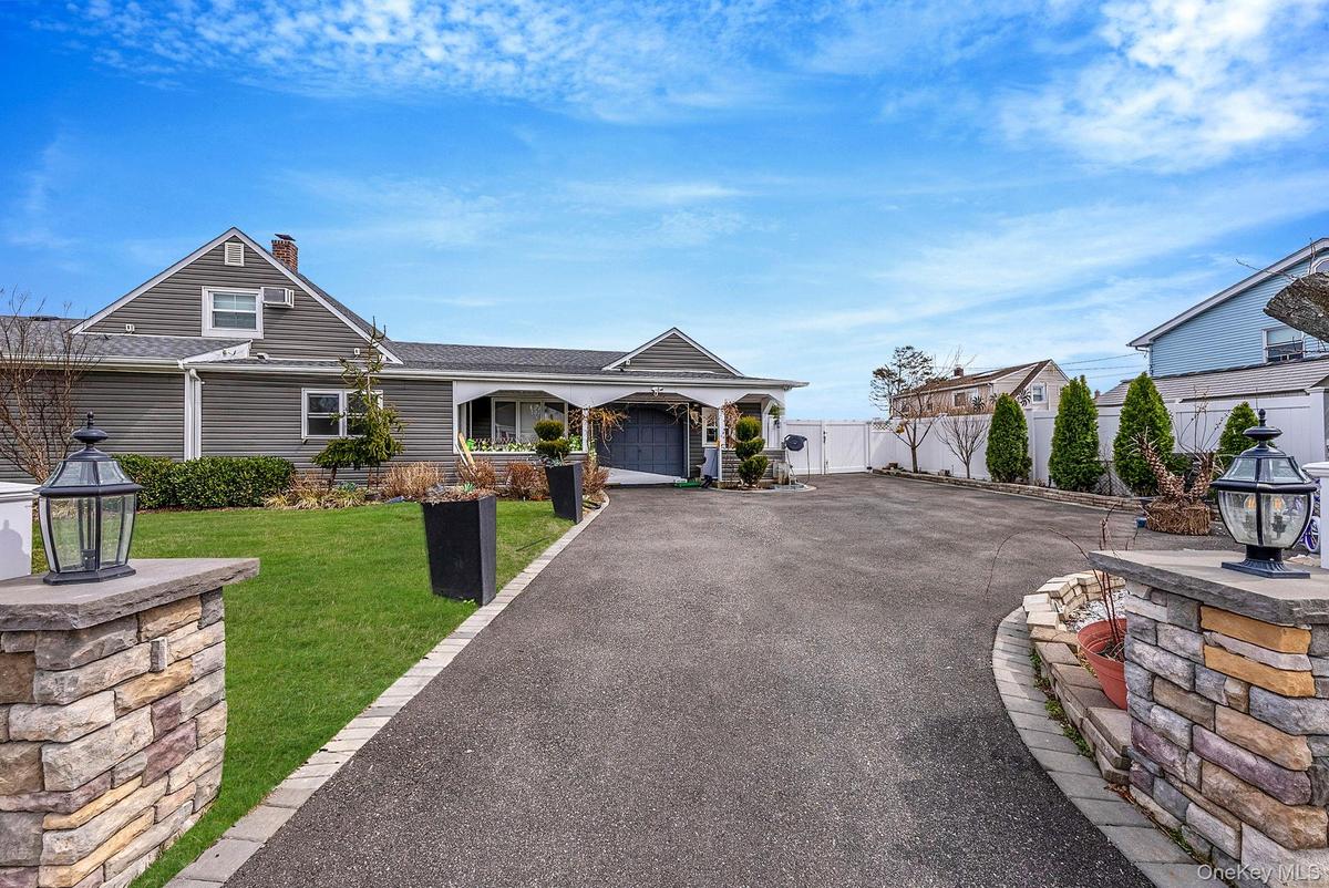 View of front of home featuring asphalt driveway, a garage, roof with shingles, and a gate
