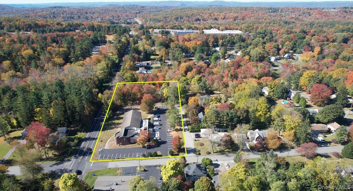 Aerial overview of property's location with a heavily wooded area and property parcel outlined