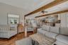 Living area featuring beamed ceiling, wood floors, and a ceiling fan