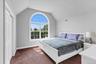Arched window with gridded panes, high vaulted ceiling, light gray wall paint,, and a paneled closet door