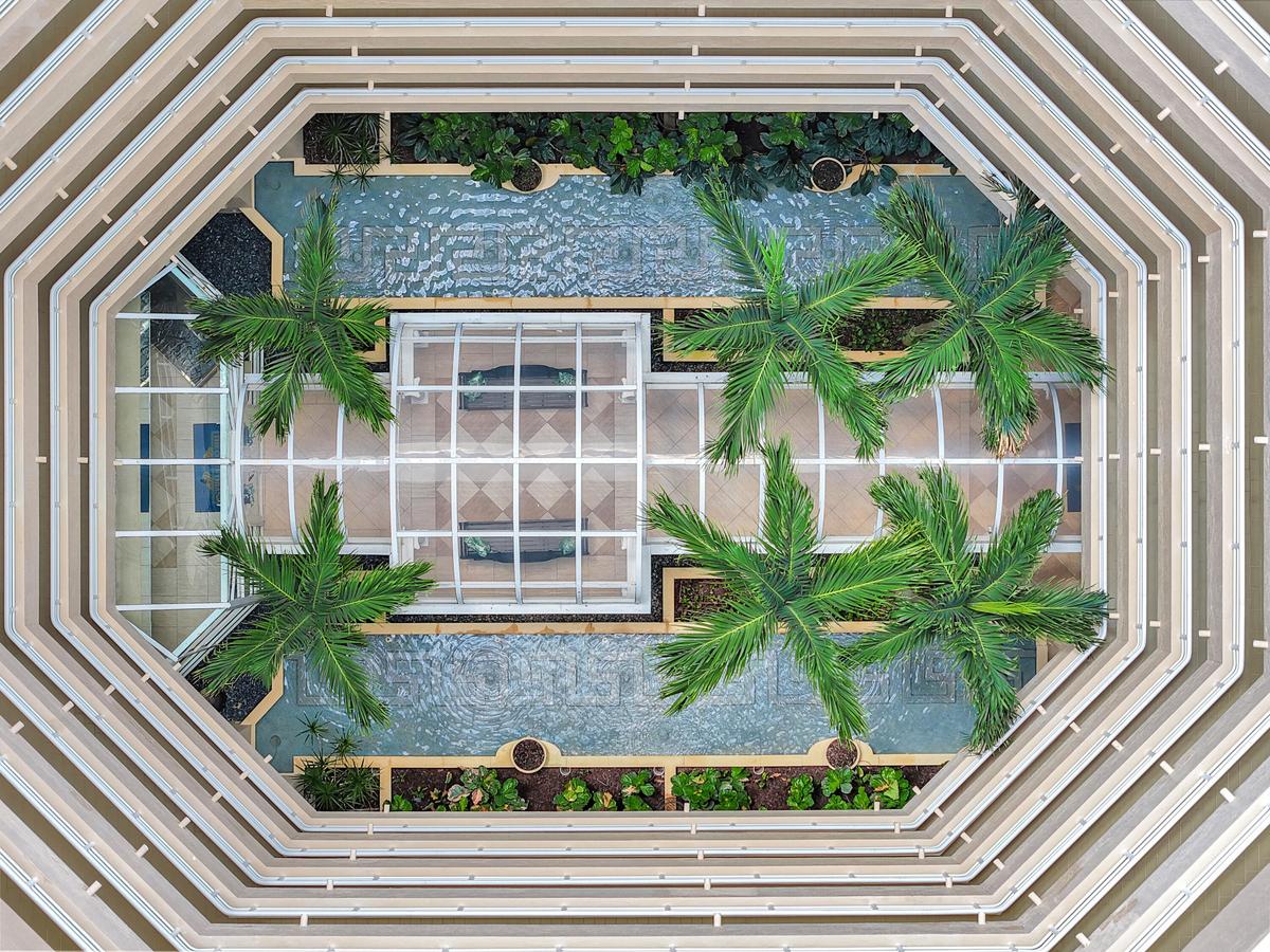 Birds-eye view of the stunning open-air atrium, bringing natural light and tropical beauty to the heart of the building.