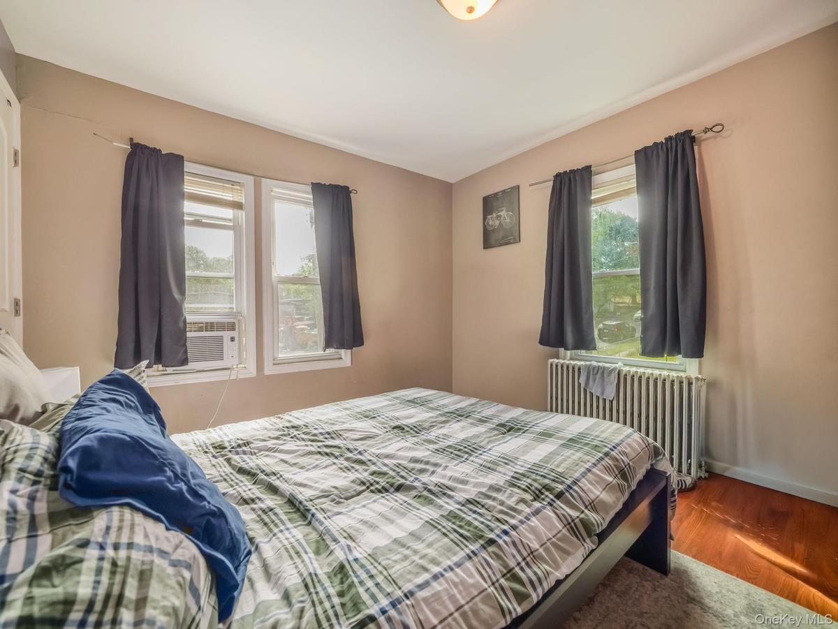 Bedroom featuring radiator heating unit, wood finished floors, and cooling unit