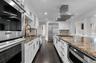 Kitchen featuring stainless steel appliances, crown molding, dark stone counters, range hood, and white cabinetry