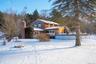 Snow covered rear of property with a chimney