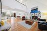 Living room featuring a tiled fireplace, high vaulted ceiling, light hardwood / wood-style floors, and a baseboard heating unit