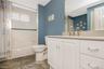 White subway tile shower surround with a decorative accent band, built-in tub, and a vanity with a light-colored countertop