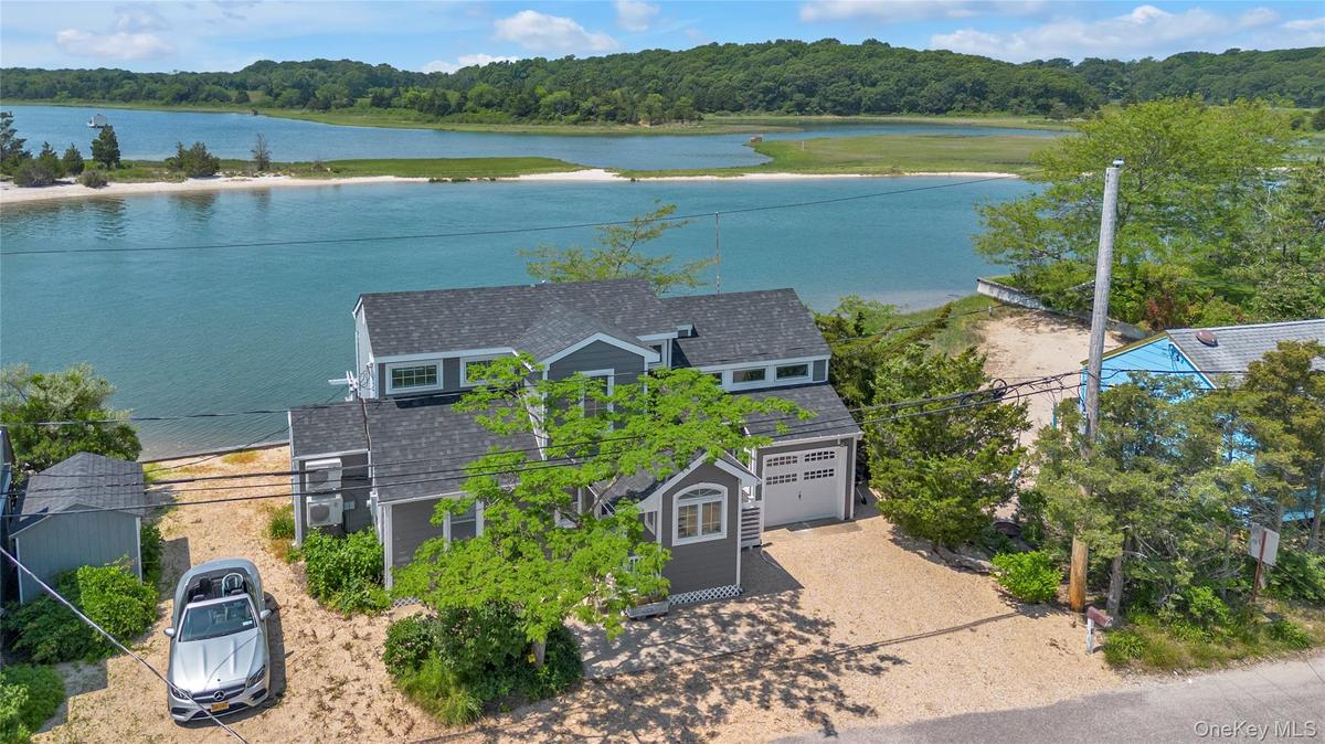 Aerial view of property and surrounding area featuring a heavily wooded area and a nearby body of water