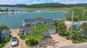 Aerial view of property and surrounding area featuring a heavily wooded area and a nearby body of water