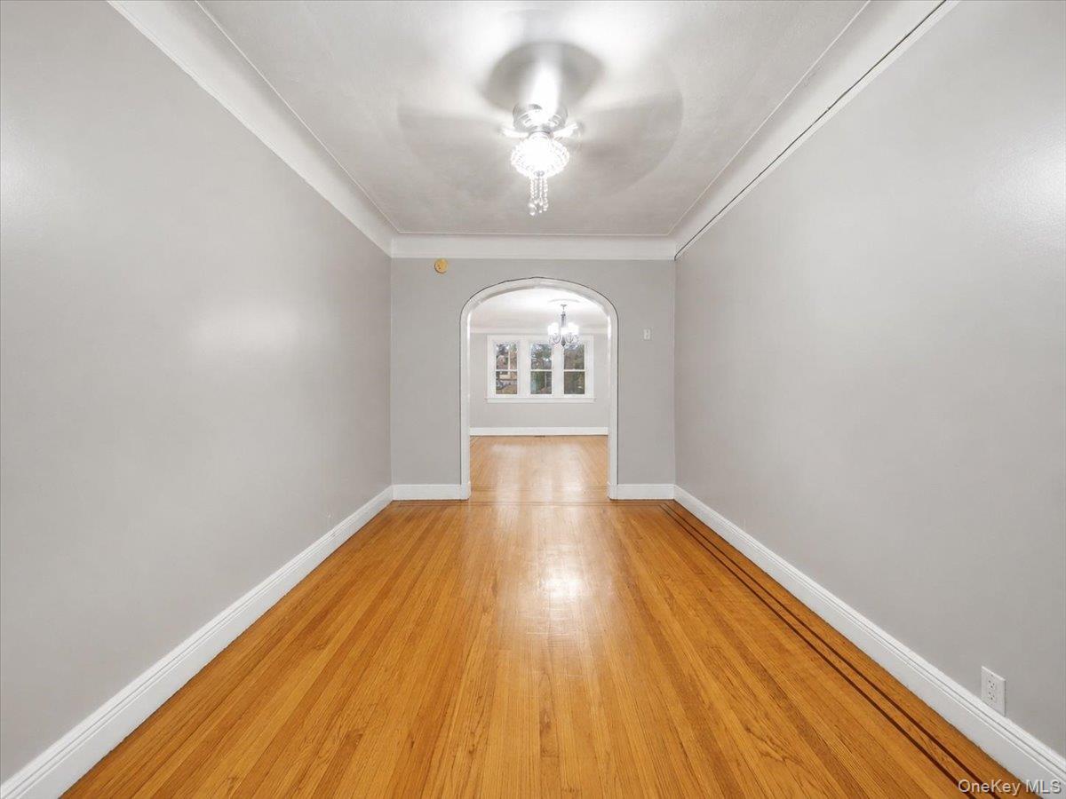 Hardwood flooring, arched doorway, recessed ceiling, flush mount chandelier, light gray wall paint