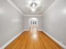 Hardwood flooring, arched doorway, recessed ceiling, flush mount chandelier, light gray wall paint