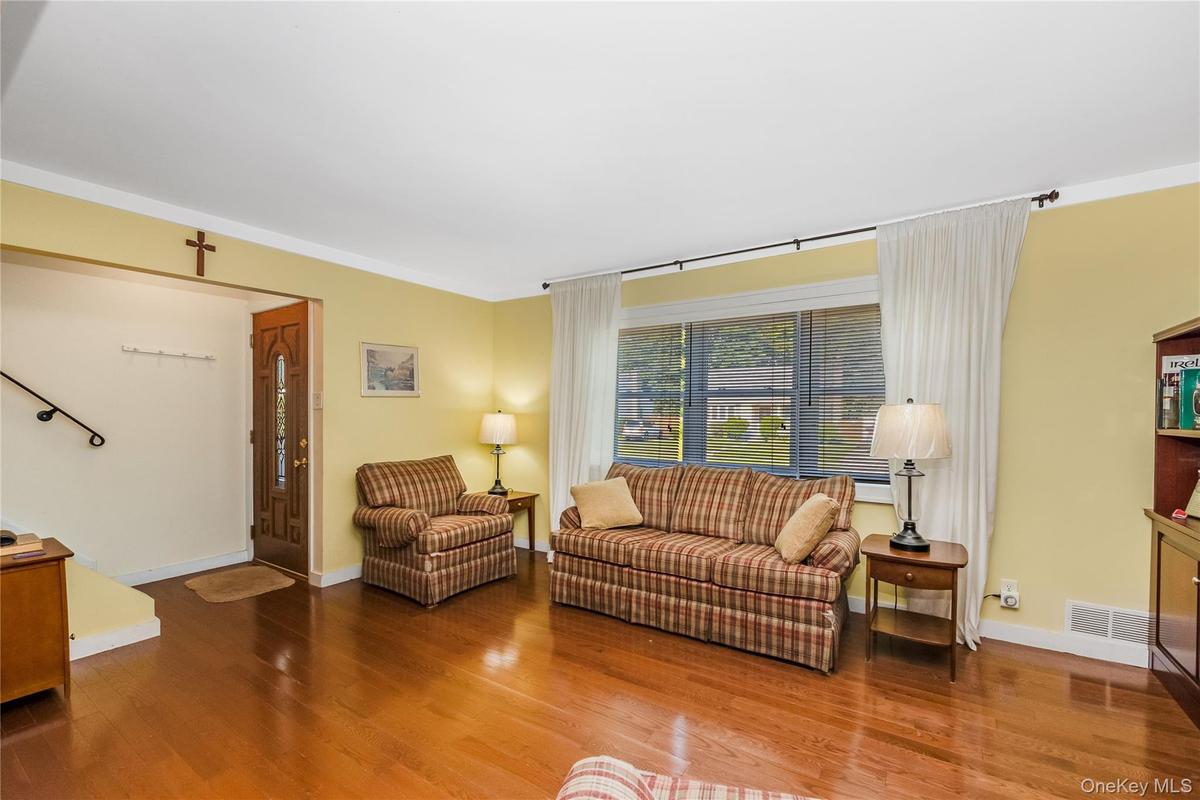 Hardwood flooring throughout, a decorative front entry door, and a large front-facing window
