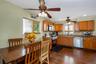 Kitchen and dining area featuring wood-finish flooring, wood cabinetry, stainless steel appliances, and ceiling fans with integrated lighting