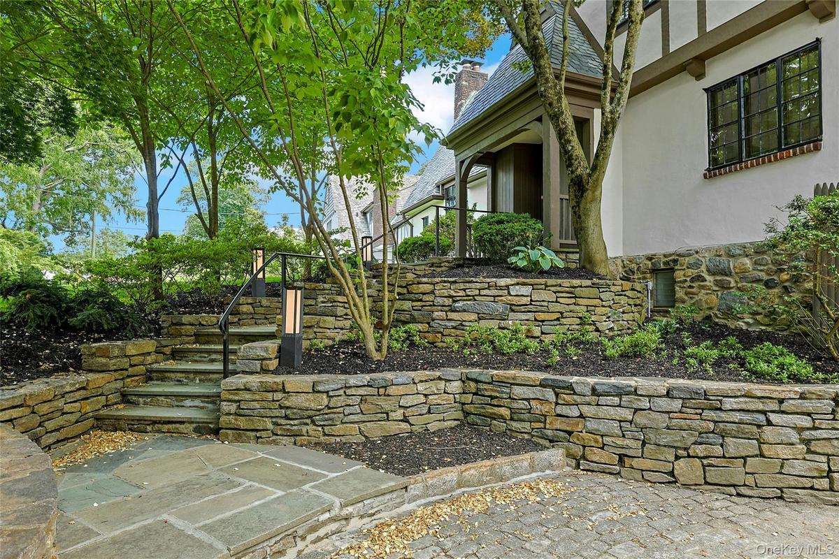 Extensive stacked stone masonry adorns the facade of this beautiful Tudor boasting a radiant heated driveway, steps and front path for winter safety a