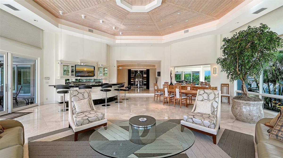 Soaring vaulted great room with a bar, dining, and lounge areas, seamlessly oriented to showcase the dramatic circular kitchen
