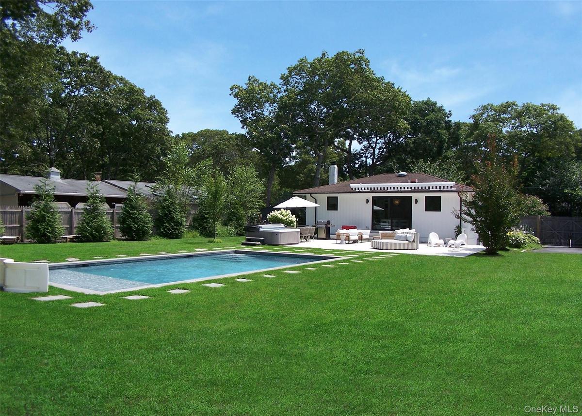View of swimming pool featuring a hot tub, a patio, view of scattered trees, and a grill