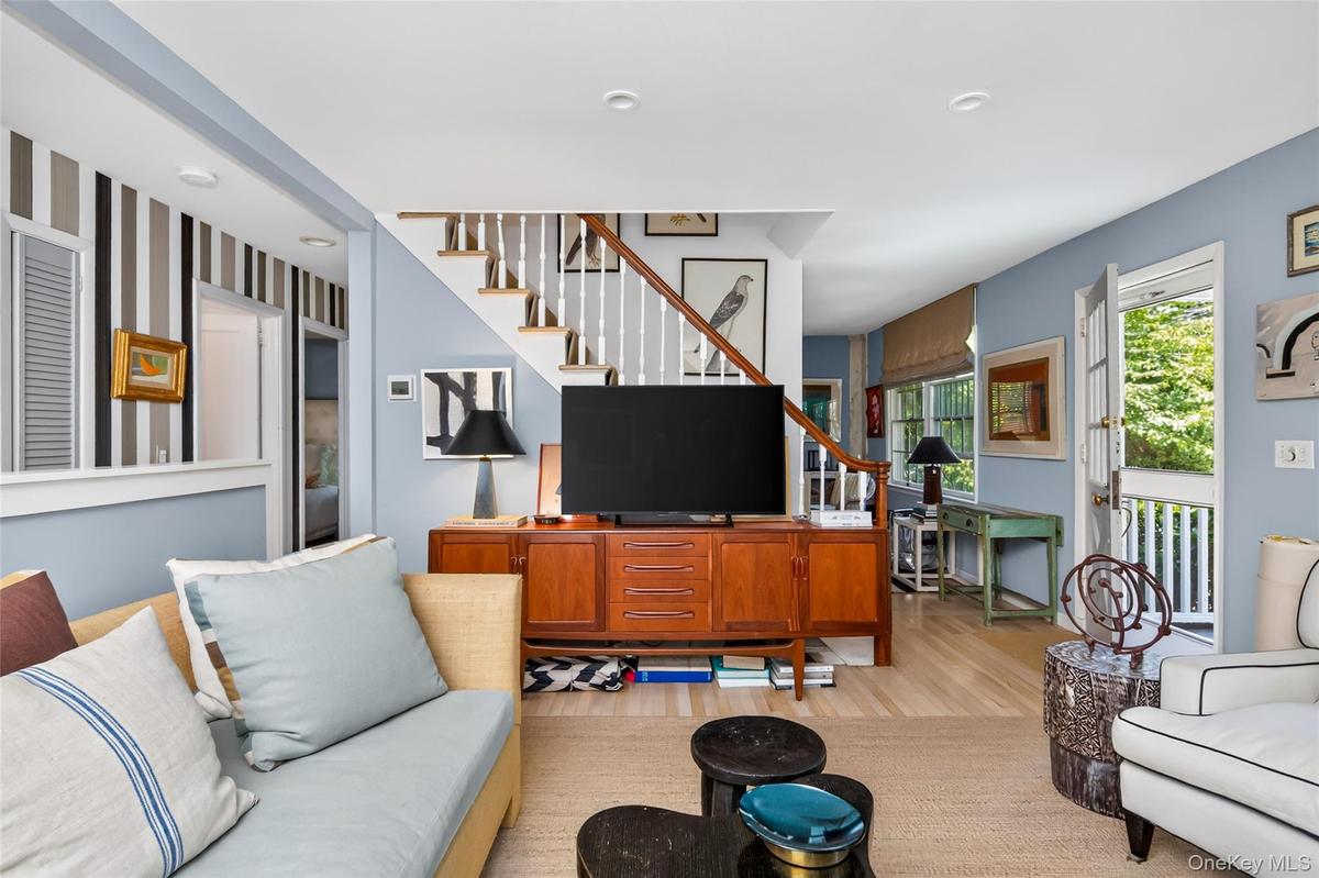 Open-concept living space with light wood-finish flooring, a contemporary staircase featuring white risers and wood treads, and white balusters