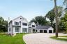 Modern farmhouse with gravel driveway, board and batten siding, an attached garage, a standing seam roof, and a chimney
