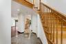 Entry foyer featuring speckled flooring, a natural wood staircase with balusters, recessed lighting, and a doorway opening to a room with dark wood-fi