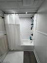 Bathroom featuring shower / tub combo, dark wood-type flooring, and wainscoting