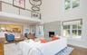 Two-story living area featuring a stone fireplace with a raised hearth, high ceilings, and wood-finish flooring