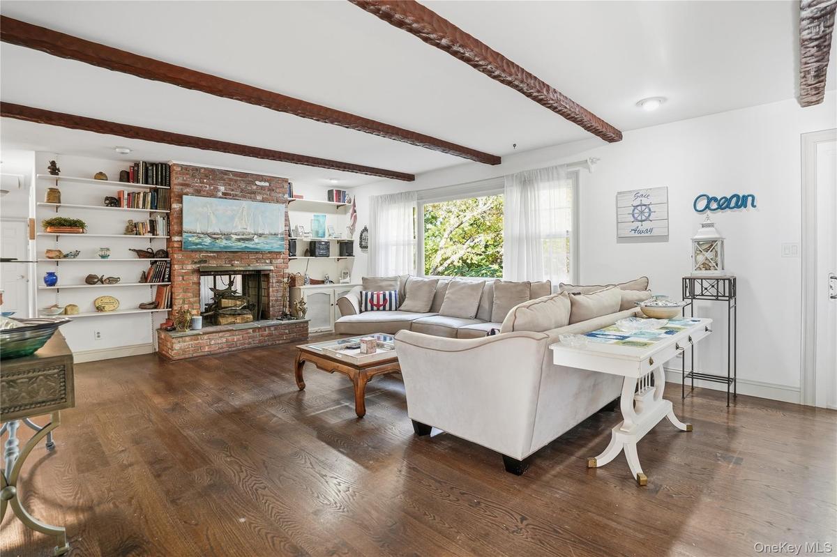 Living room featuring beam ceiling, dark wood-style flooring, and a fireplace