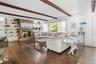 Living room featuring beam ceiling, dark wood-style flooring, and a fireplace