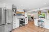 Kitchen featuring stainless steel appliances, white cabinets, open floor plan, a warm lit fireplace, and ornamental molding
