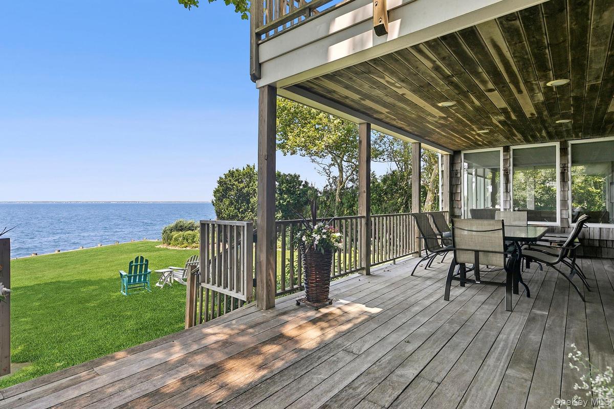 Deck featuring a water view, a lawn, and outdoor dining area