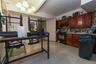 Kitchen featuring backsplash, light tile patterned flooring, gas stove, under cabinet range hood, and a chandelier