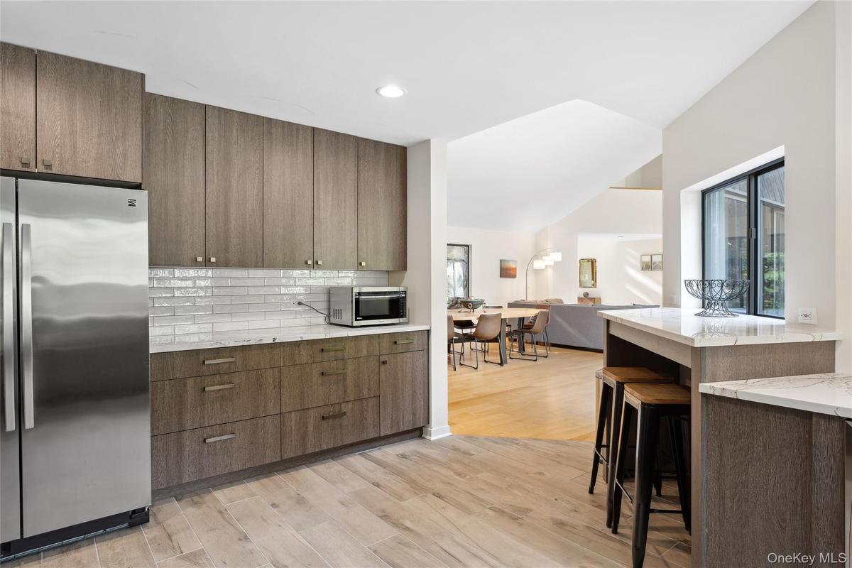 Kitchen with stainless steel appliances, light stone countertops, decorative backsplash, light wood-style floors, and open floor plan