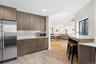Kitchen with stainless steel appliances, light stone countertops, decorative backsplash, light wood-style floors, and open floor plan