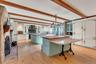 Kitchen featuring green cabinetry, a kitchen breakfast bar, a fireplace, light wood-style flooring, and butcher block counters