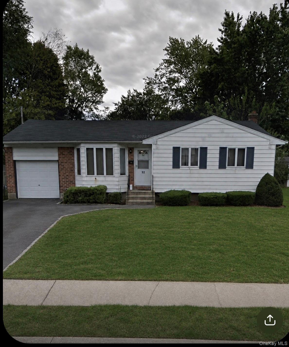 Ranch-style residence featuring white siding, a brick facade, bay windows, and a single-car garage