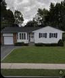 Ranch-style residence featuring white siding, a brick facade, bay windows, and a single-car garage