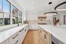 Kitchen with glass insert cabinets, white cabinetry, light stone counters, decorative backsplash, and recessed lighting