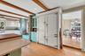 Kitchen with green cabinets, glass insert cabinets, white cabinetry, light wood-style flooring, and beamed ceiling