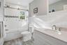 Full bath with vanity, combined bath / shower with glass door, and light wood-style floors
