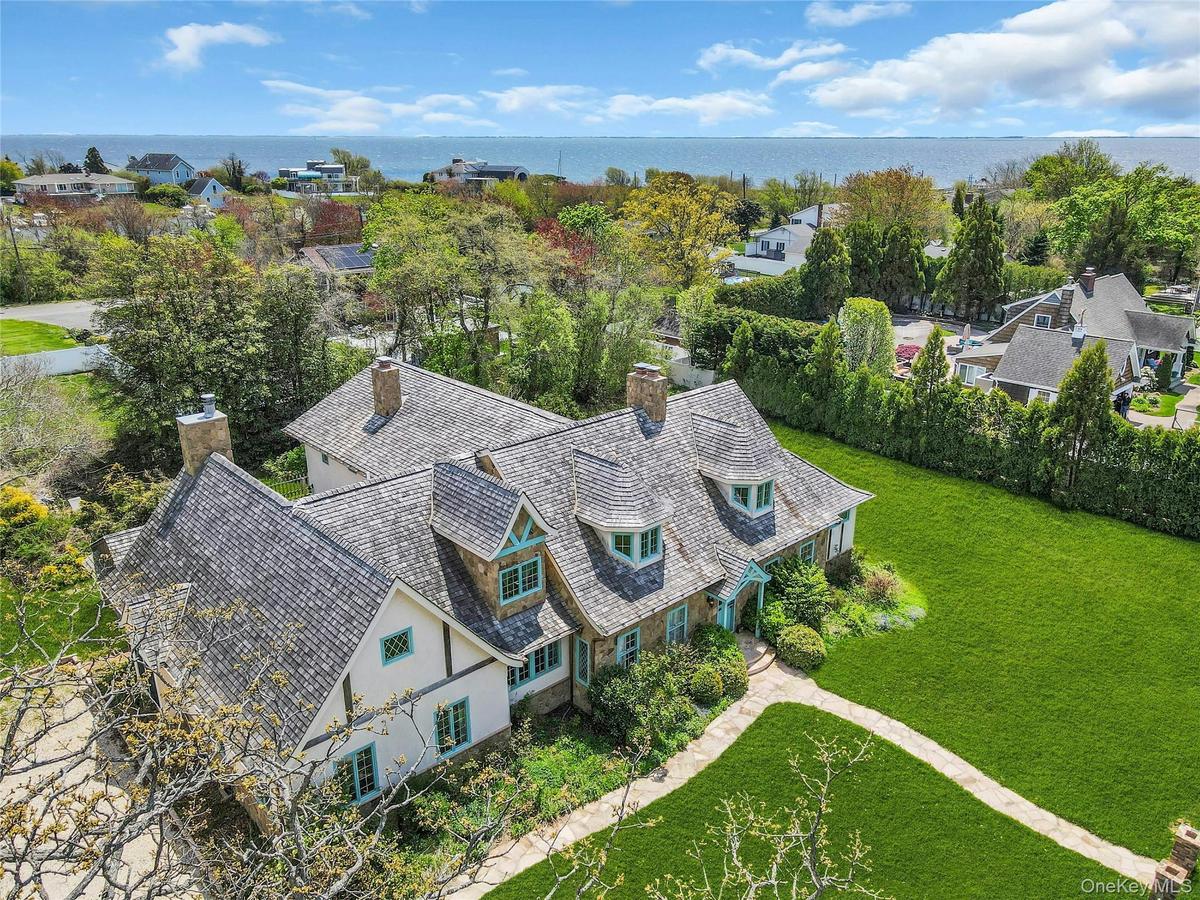 Stone and stucco residence featuring multiple dormers, a cedar shake roof, and a stone walkway
