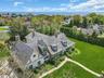 Stone and stucco residence featuring multiple dormers, a cedar shake roof, and a stone walkway