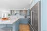 Kitchen featuring high end refrigerator, a sink, light wood finished floors, a kitchen bar, and recessed lighting
