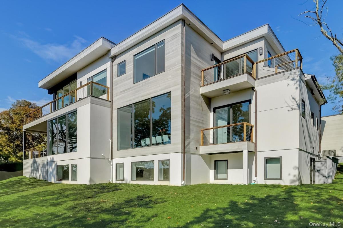 Rear view of house with a lawn and a balcony